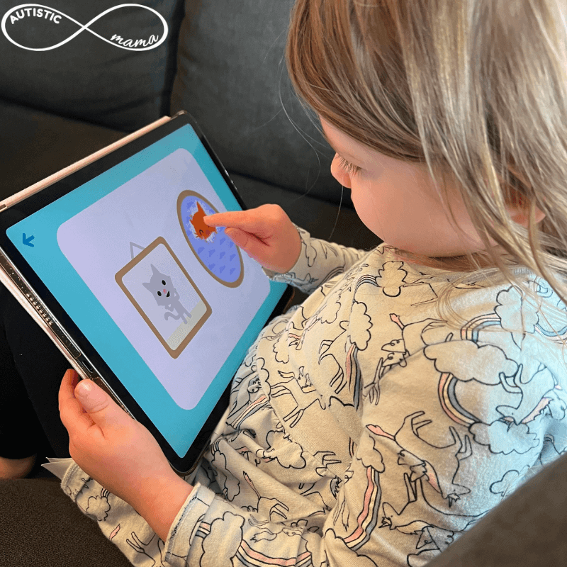 Child sitting down and pointing at a tablet screen showing the SAGO Mini First Words App