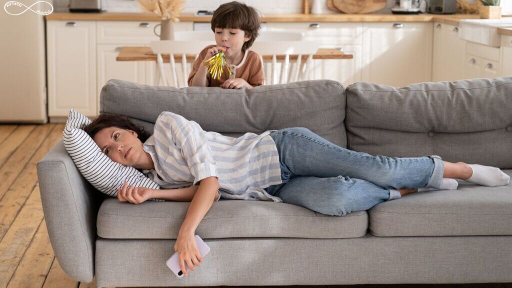 Mom lays on the couch with a kid behind the couch sipping juice.